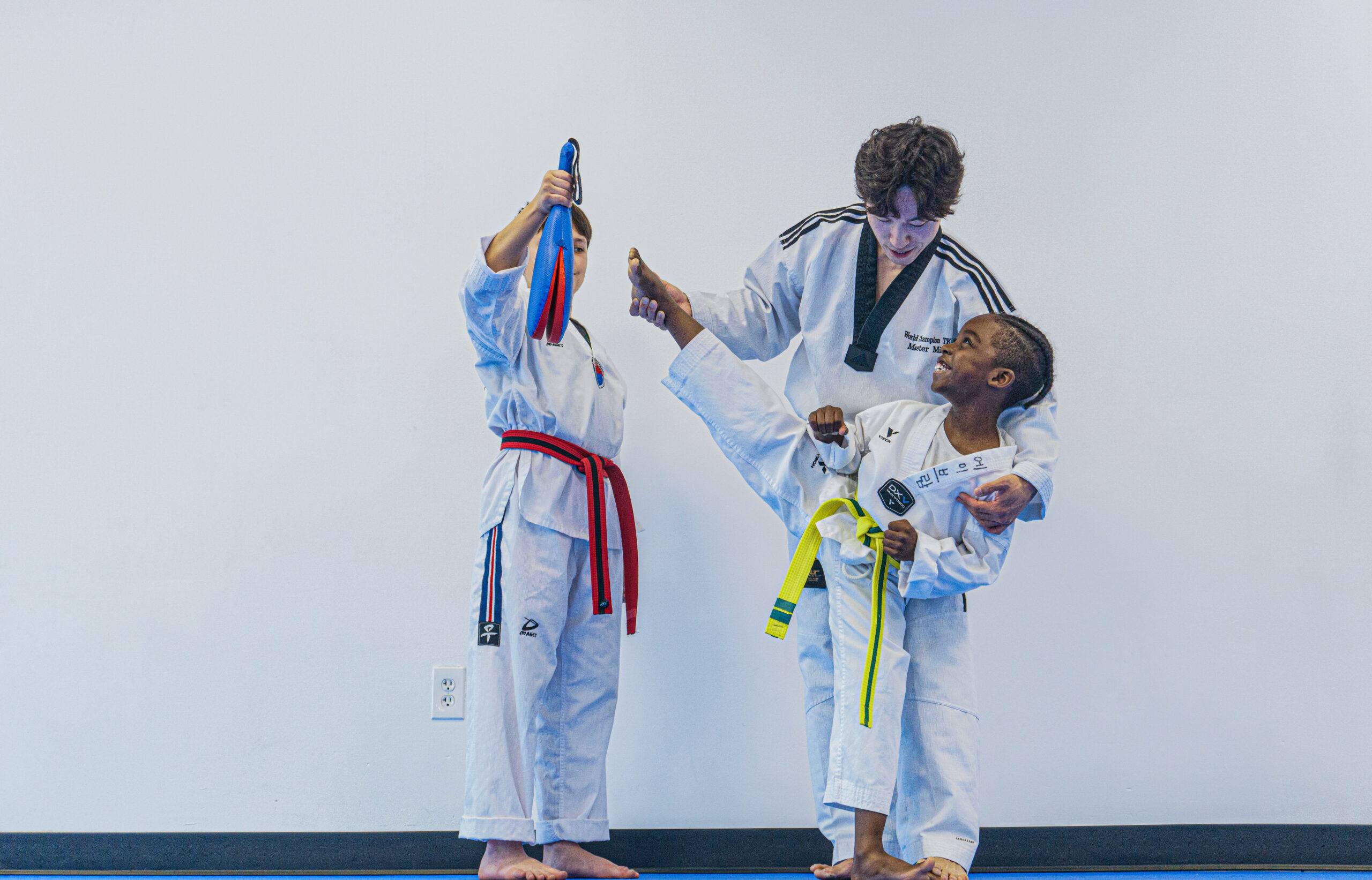 Instructor coaching two young students during a Taekwondo class