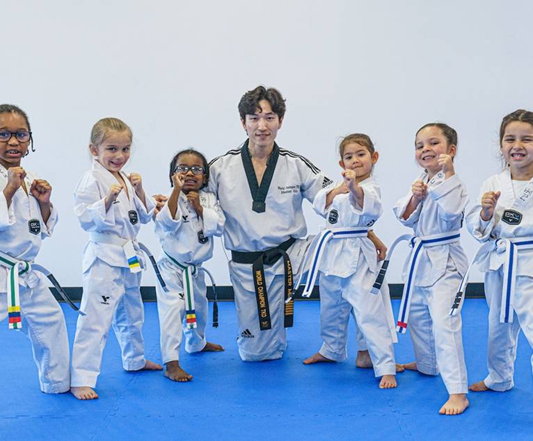 Instructor kneeling with a group of Little Tigers students in a ready stance