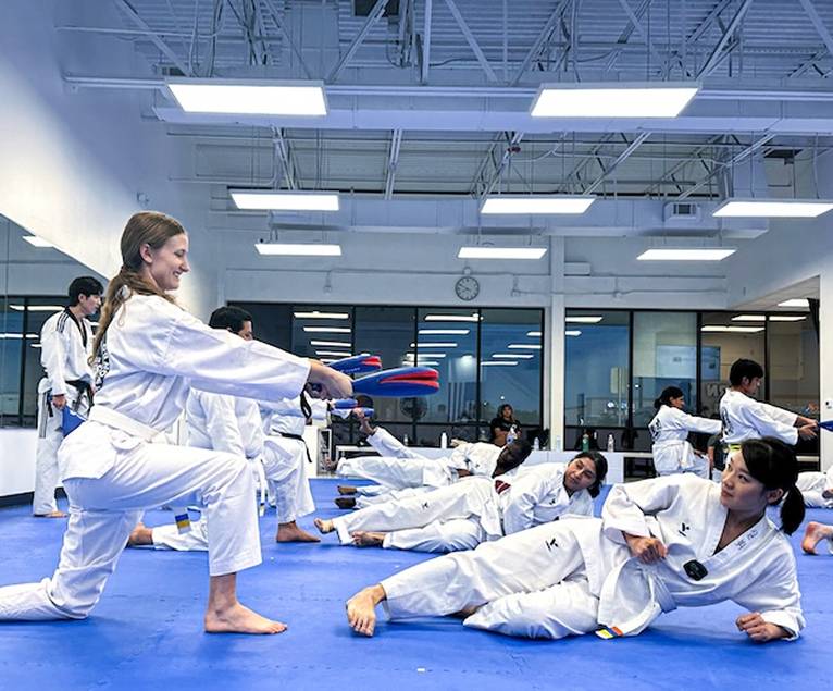 Teen and adult students practicing kicks on the mat