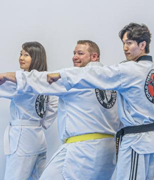 Teen and adult students practicing a punch together in class