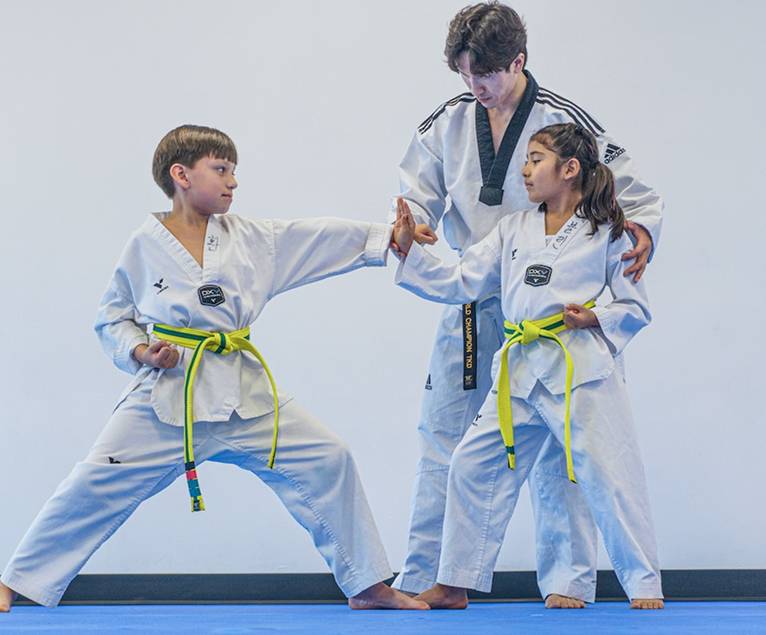 Instructor correcting the stance of two youth students